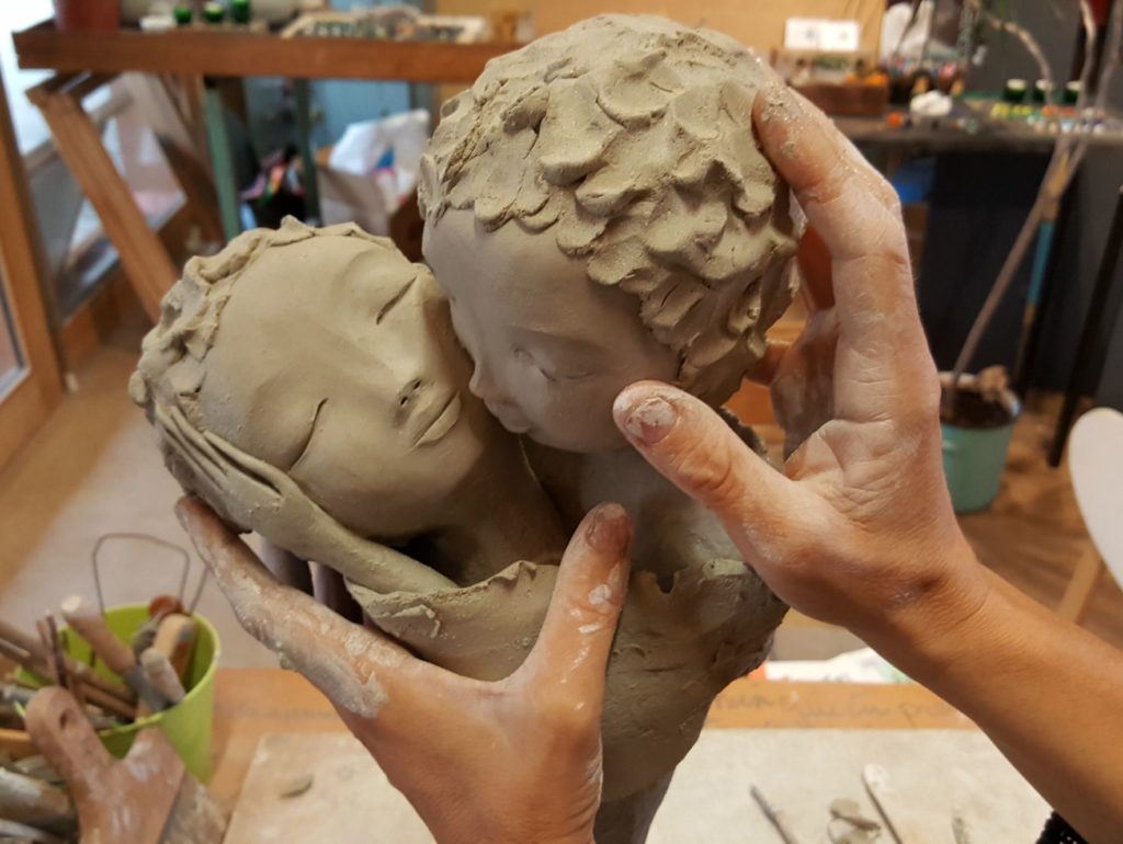 Lydie Thonnerieux sculptant deux personnages, zoom sur ses mains elle modèle deux visages